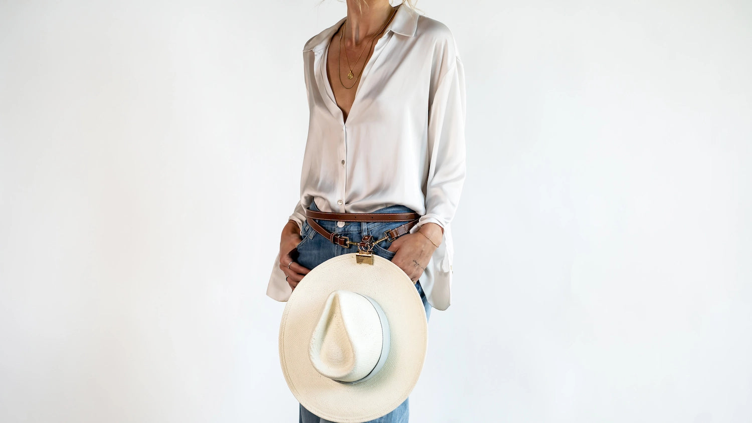Waist style shown wearing the Sidecar The OG 14K gold hat clip with genuine brown leather side strap, white stitching, and adjustable leather strap with 14k hardware. Luxury, hands-free hat carry worn in 4 styles: Crossbody, Backpack, Purse-style, and Waist-wear.