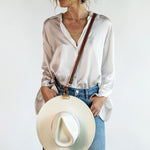 Crossbody Style shown wearing the Sidecar The OG 14K gold hat clip with genuine brown leather side strap, white stitching, and adjustable leather strap with 14k hardware. Luxury, hands-free hat carry worn in 4 styles: Crossbody, Backpack, Purse-style, and Waist-wear.