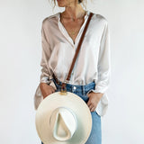 Crossbody Style shown wearing the Sidecar The OG 14K gold hat clip with genuine brown leather side strap, white stitching, and adjustable leather strap with 14k hardware. Luxury, hands-free hat carry worn in 4 styles: Crossbody, Backpack, Purse-style, and Waist-wear.