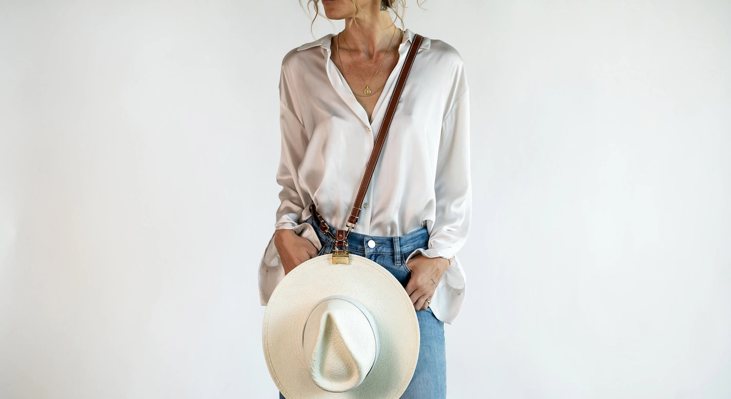 Crossbody Style shown wearing the Sidecar The OG 14K gold hat clip with genuine brown leather side strap, white stitching, and adjustable leather strap with 14k hardware. Luxury, hands-free hat carry worn in 4 styles: Crossbody, Backpack, Purse-style, and Waist-wear.
