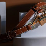 Sidecar The OG 14K gold hat clip with genuine brown leather side strap, white stitching, and adjustable leather strap with 14k hardware. Luxury, hands-free hat carry worn in 4 styles: Crossbody, Backpack, Purse-style, and Waist-wear.