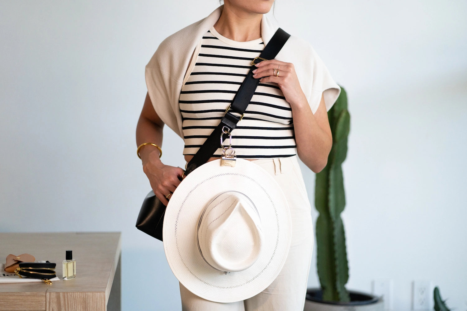 Sidecar hat clip with silver polished metal finish attached to handbag, designed to carry a hat hands-free without bending or damage. Secure, durable, luxurious.