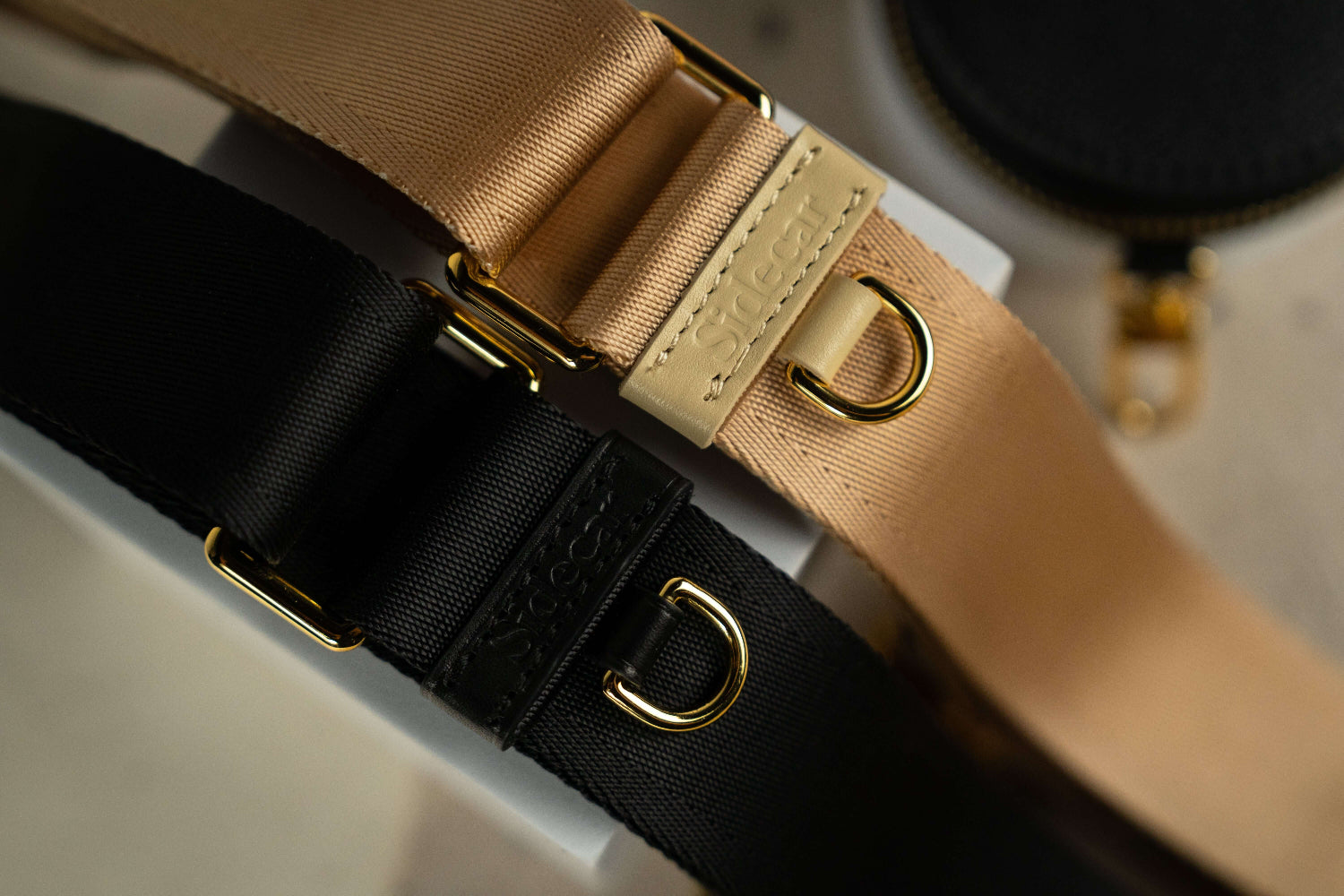 Sidecar black sable and buttercream dark neutral nylon purse strap, featuring a smooth durable design, gold accents, and adjustable length for bags. Luxurious and durable.