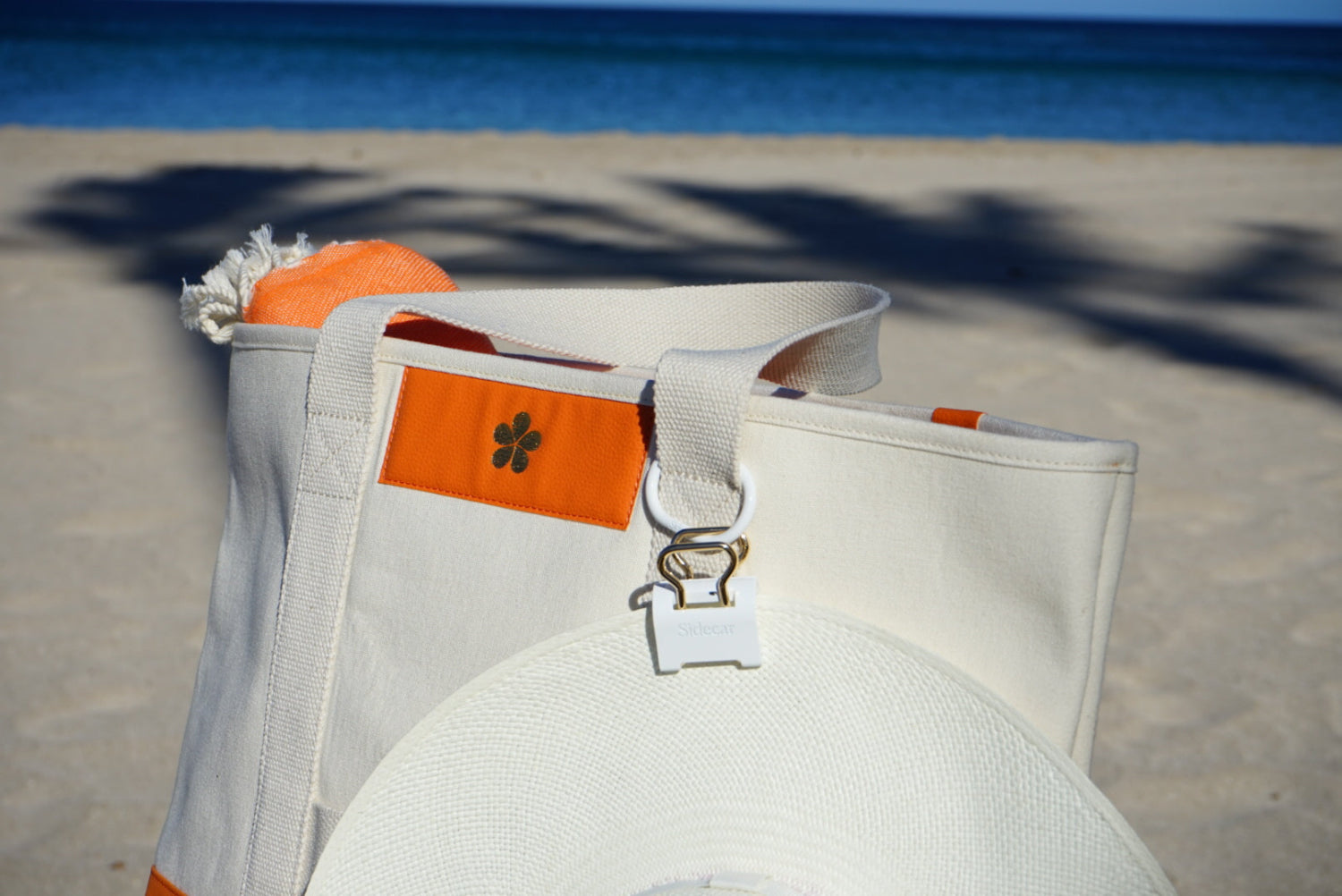 Sidecar White Duo Set with 14K Gold Hardware. Patented hat clip in white holding a white hat, attached to a travel beach bag.Hands-free hat carrying without bending or damage.