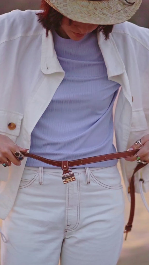 Waist-wear Style shown wearing the Sidecar The OG 14K gold hat clip with genuine brown leather side strap, white stitching, and adjustable leather strap with 14k hardware. Luxury, hands-free hat carry worn in 4 styles: Crossbody, Backpack, Purse-style, and Waist-wear.